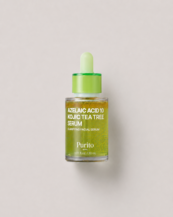 A korean skincare serum - Purito Azelaic Acid 10 Kojic Tea Tree Serum in a clear glass dropper bottle with a bright green cap and dropper, set against a solid light gray background. 30 ml.