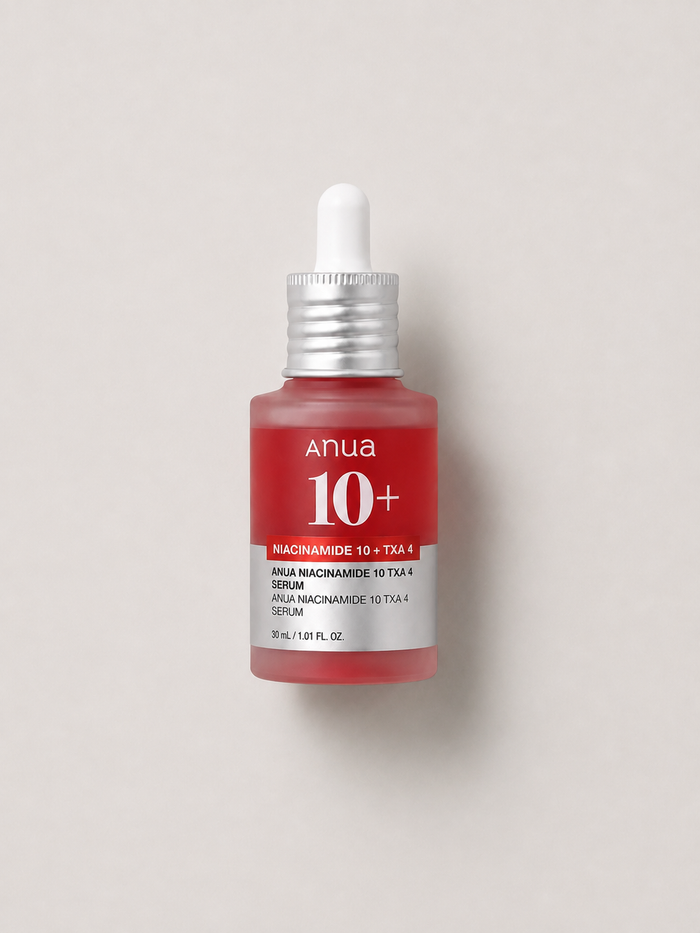 A korean skincare serum - Anua Niacinamide 10 + TXA 4 Serum in a frosted glass dropper bottle with a red liquid and silver cap, set against a neutral light gray background. 30 ml.