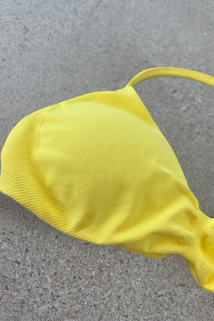 Minimalistic bra with breast contouring panels and a ruched front seam to effortlessy shape the breasts, with a sleek back straps and halter neck design for showcasing the back gains in buttercup yellow