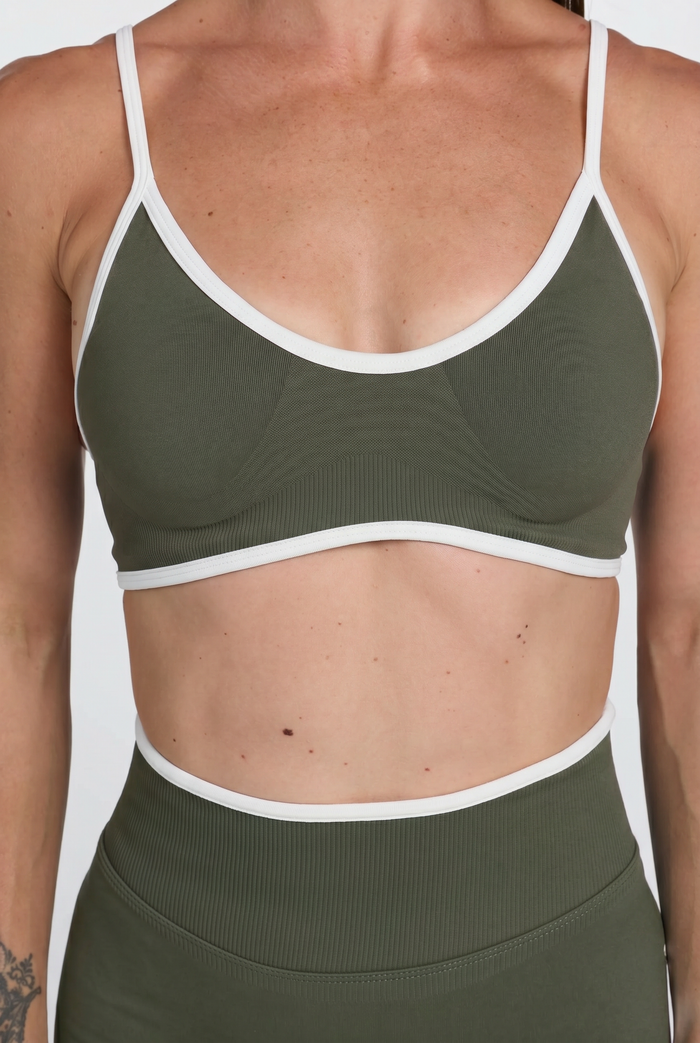 Person wearing an army green sports bra with white trim on a white background