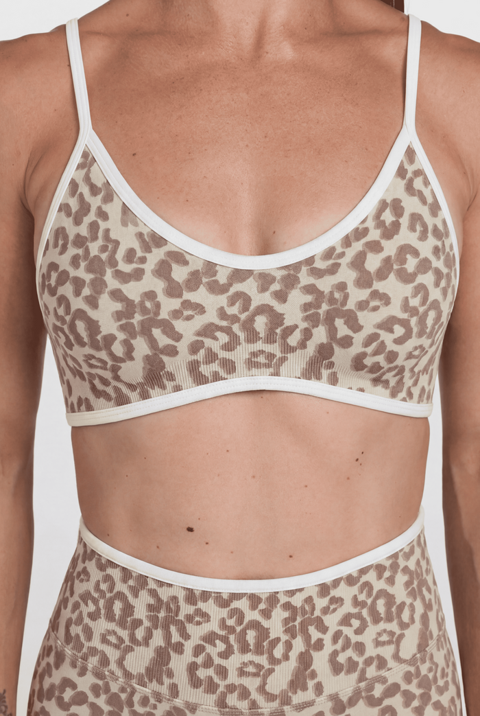 Cream leopard print sports bra and shorts set with white trim on a plain background