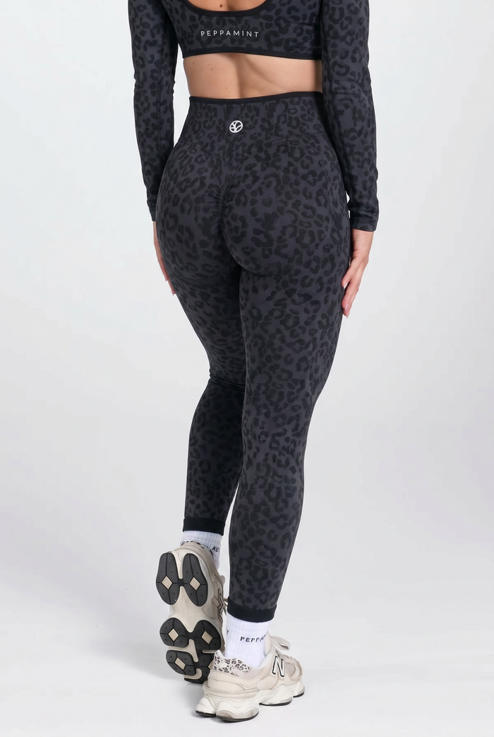 Person wearing black leopard print leggings and a matching top on a white background