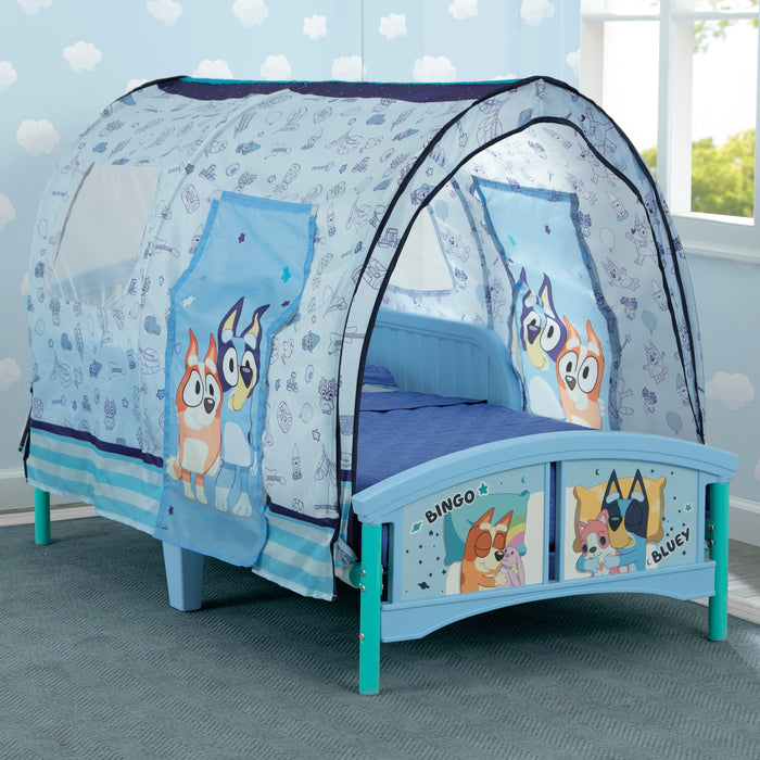 Children's bed with a blue and white canopy featuring cartoon characters in a room with light blue walls.
