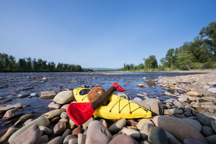 P.L.A.Y. Camp Corbin K9 Kayak Toy on rocks with lake in the background