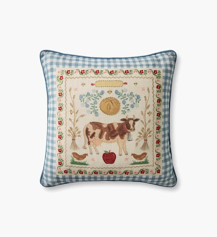 Decorative pillow with a cow and farm-themed embroidery on a blue checkered background
