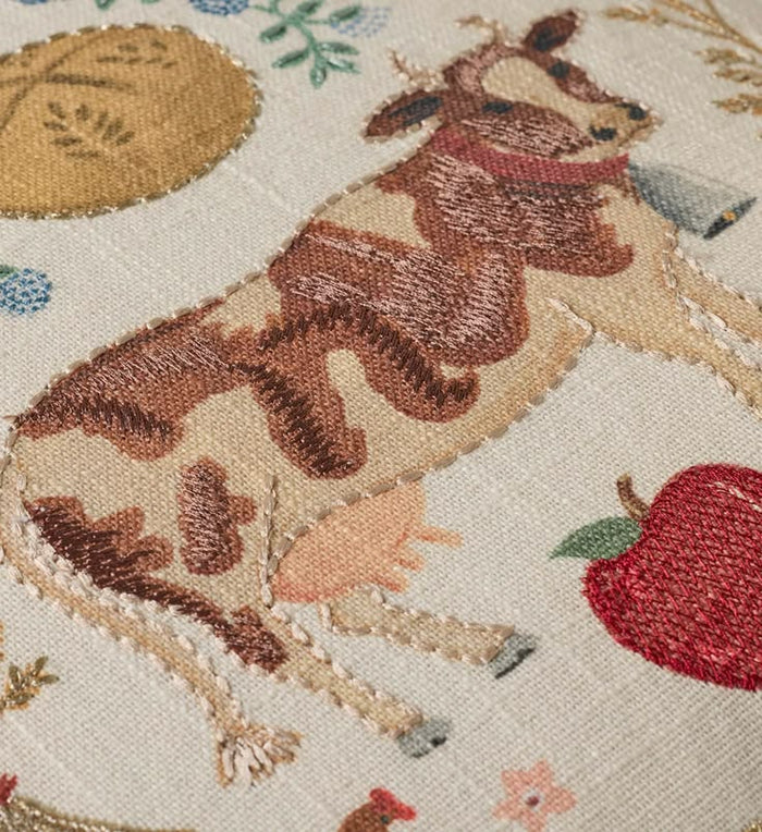 Embroidered design of a deer with flowers and an apple on a beige background