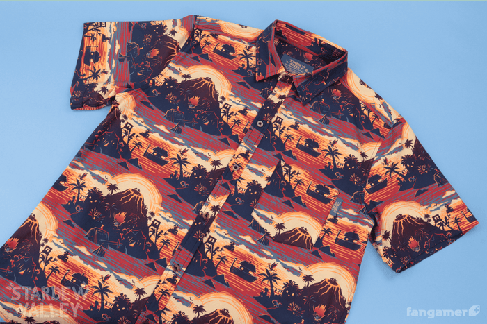 A short-sleeve button-up Stardew Valley shirt with a repeating Ginger Island pattern in sunset colors—bronze, orange, red. It's photographed against a light blue background.