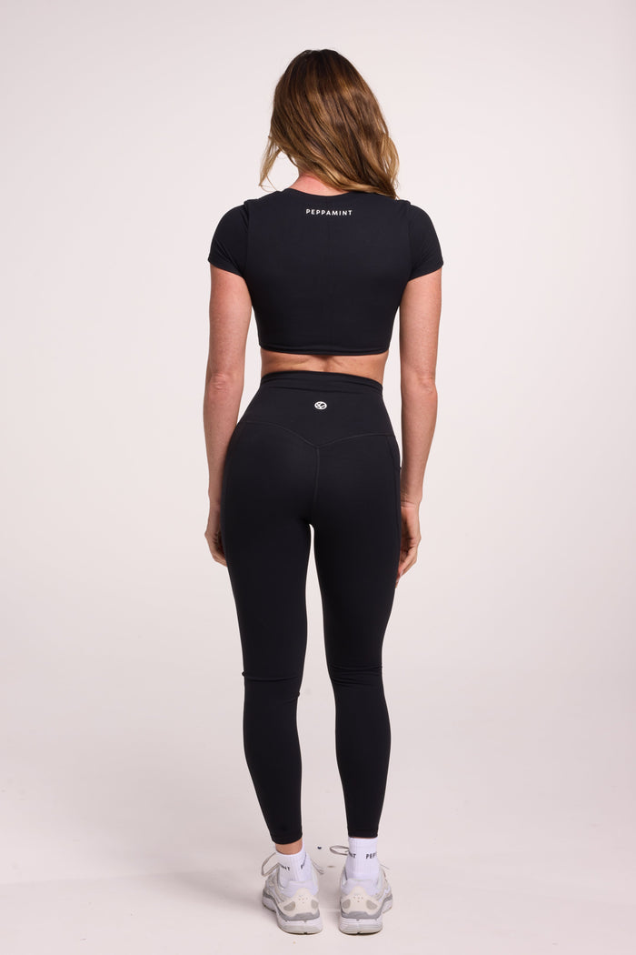 Buttery soft high waisted women's gym tights with practical pockets, sweetheart back seams for an upper glute shaping effect, and no front rise seam, paired with an V neck women's crop t-shirt with a supportive elasticated hem and triple layered fabric with removable pads for extra support in black