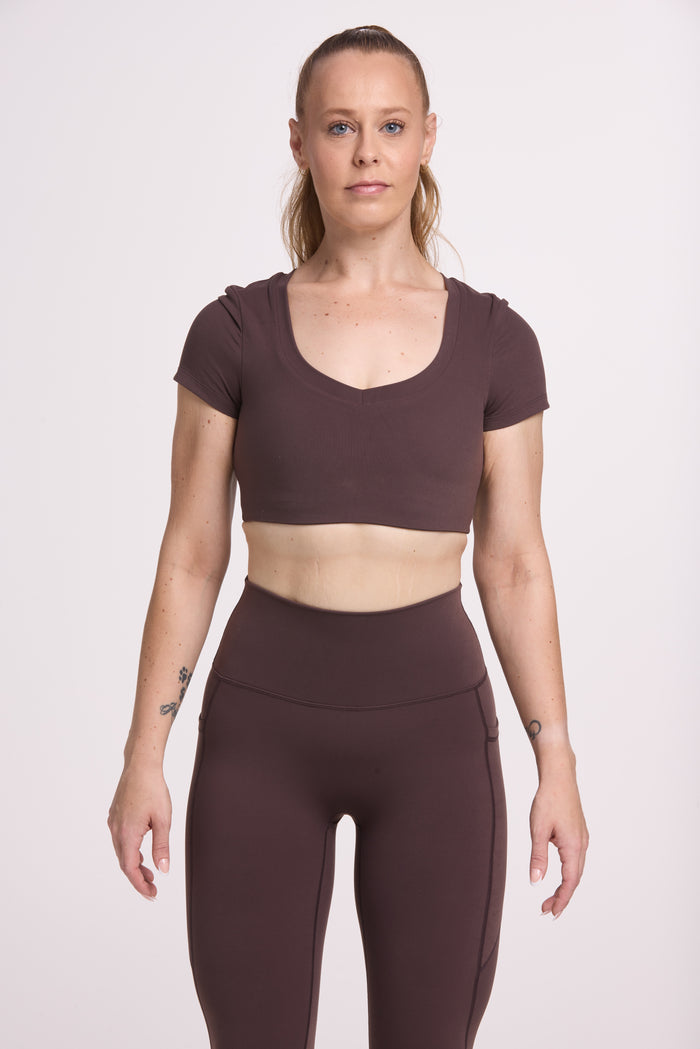 Buttery soft high waisted women's gym tights with practical pockets, sweetheart back seams for an upper glute shaping effect, and no front rise seam, paired with an V neck women's crop t-shirt with a supportive elasticated hem and triple layered fabric with removable pads for extra support in chocolate
