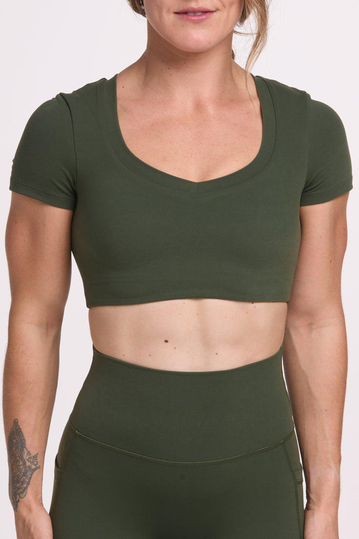 Buttery soft high waisted women's gym tights with practical pockets, sweetheart back seams for an upper glute shaping effect, and no front rise seam, paired with an V neck women's crop t-shirt with a supportive elasticated hem and triple layered fabric with removable pads for extra support in forest green