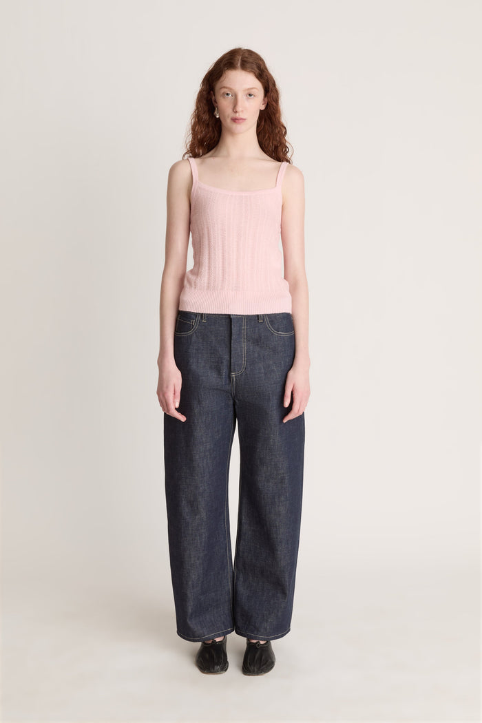 Woman wearing a pink top and dark blue jeans on a white background