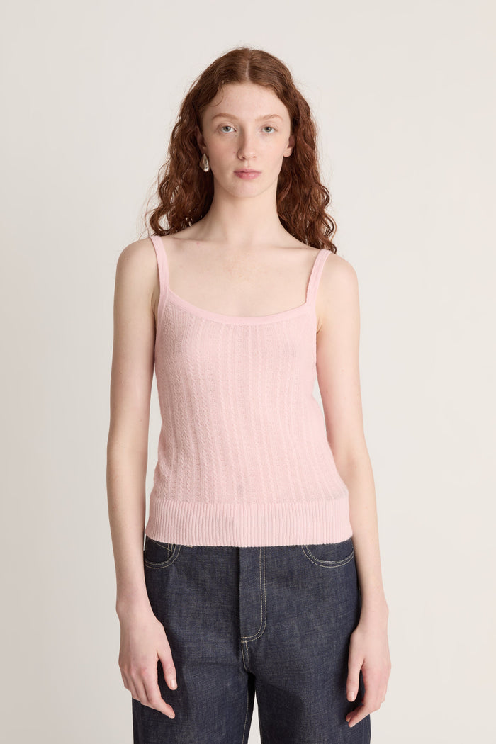 Woman wearing a pink knit top and dark blue jeans on a white background