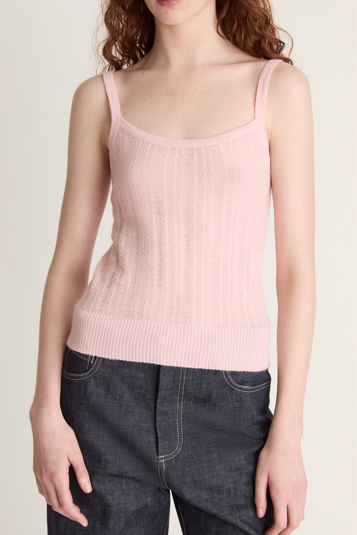 Woman wearing a pink knit top and dark blue jeans on a white background