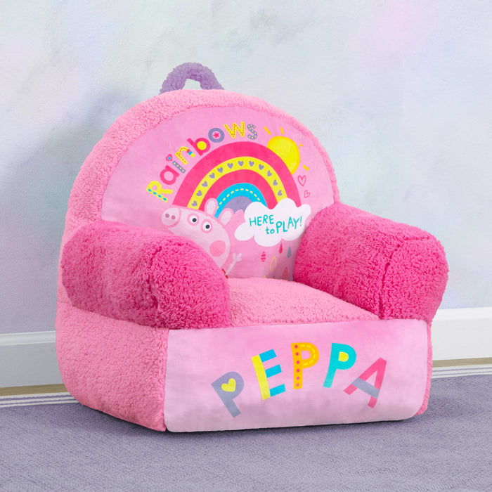 A pink Peppa Pig themed Cozee Buddy Chair with colorful graphics and a handle, placed in a room.