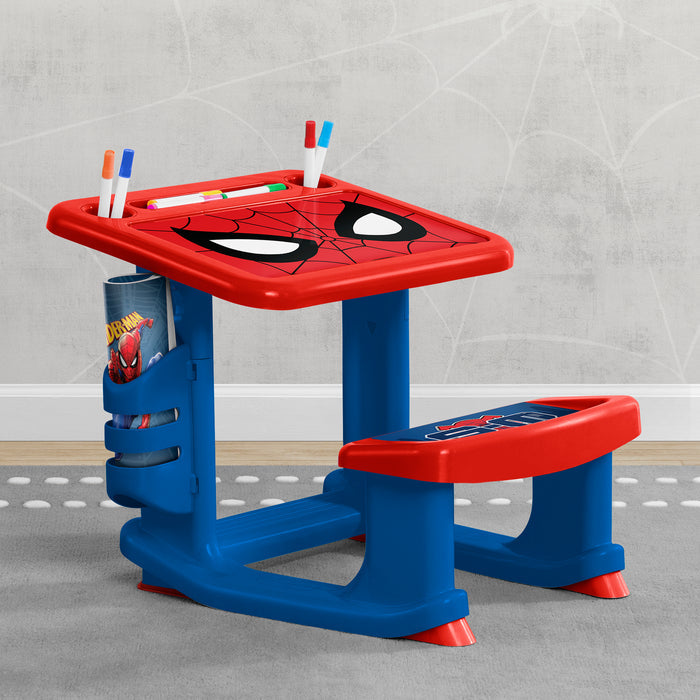Children's desk with Spider-Man design on a gray floor.