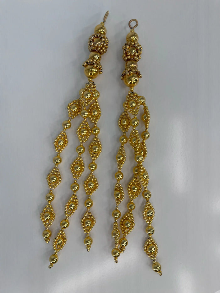 Pair of beaded medallions from polymer metal beads with 22k gold washed by object and dawn on neutral background