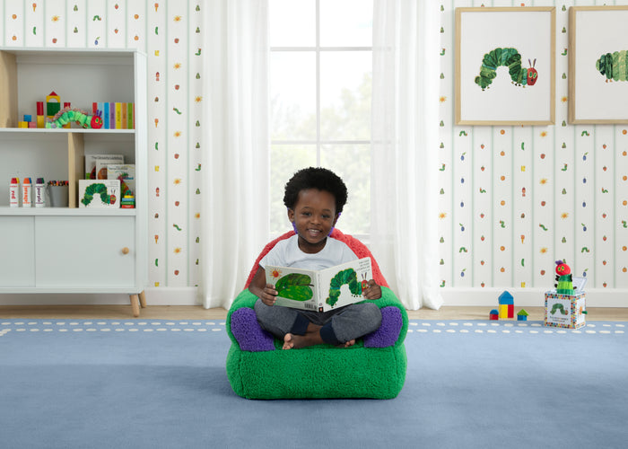 Child sitting on a green bean bag chair reading a book in a room with educational decor.